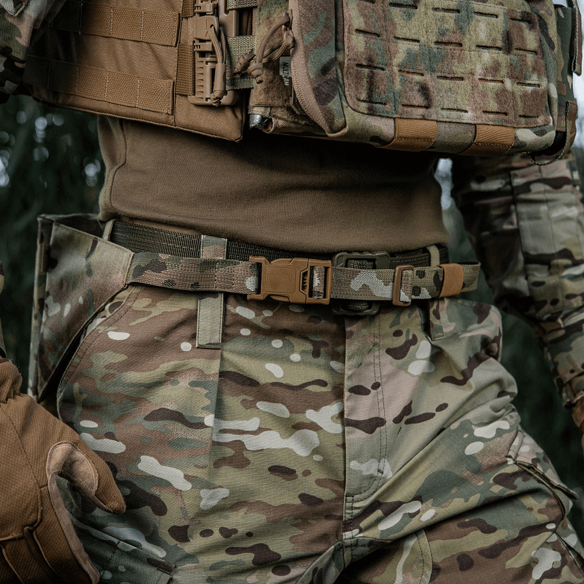 Person iført M-Tac Siddeunderlag med Bælte – Multicam i felttøj, designet til beskyttelse mod kulde og fugt.