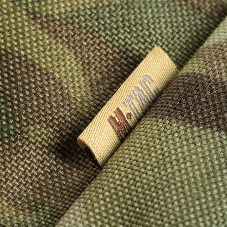 Nærbillede af M-Tac Siddeunderlag med Bælte – Multicam, viser detaljerne i multicam-camouflagemønsteret og M-Tac-mærket.