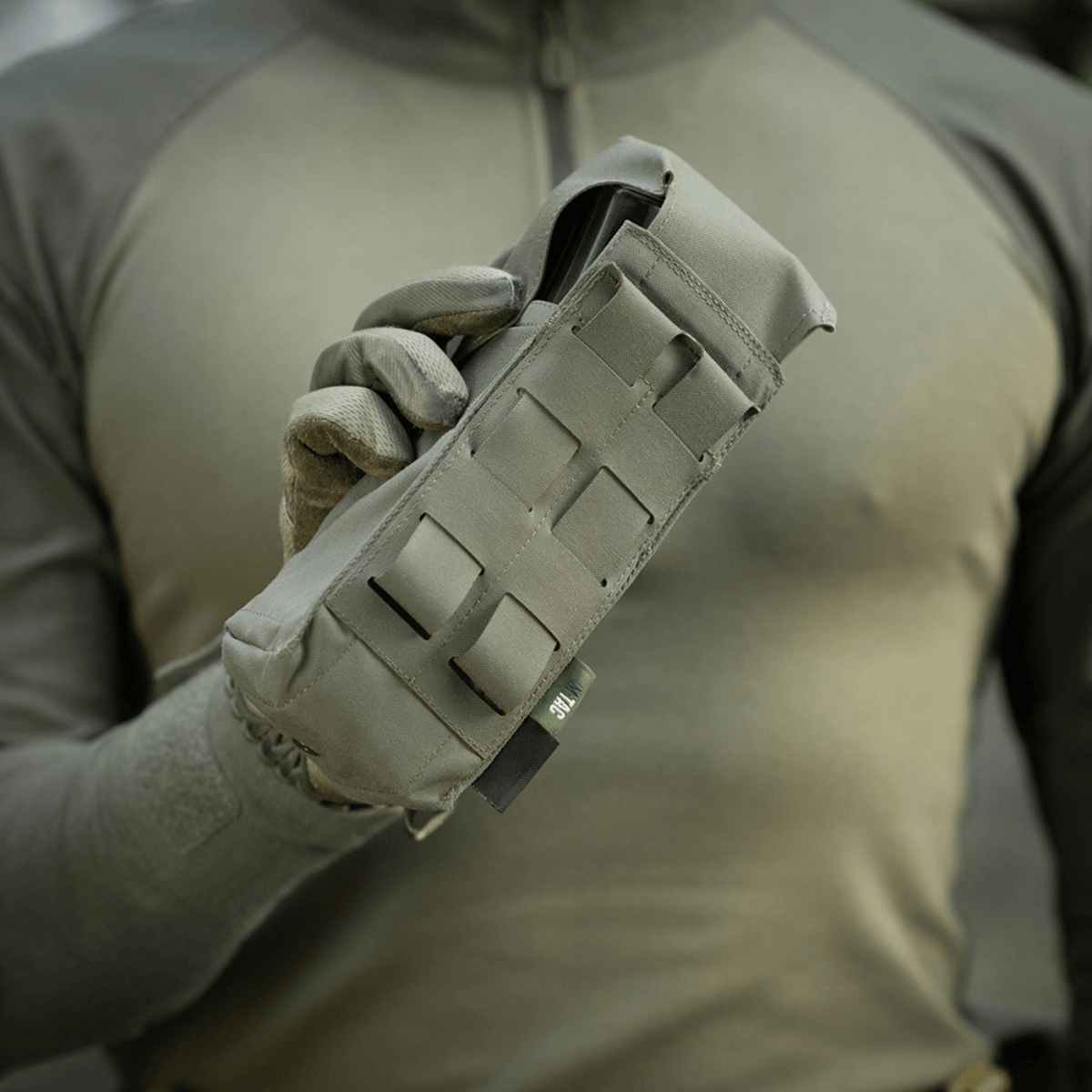 M-Tac Dobbelt Magasin Taske med Fastex Lukning holdt af mand i militærgrønt tøj, designet til AR- og AK-seriens magasiner.