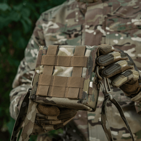 M-Tac Taske til Natkikkert PVS-14 i camouflage, holdt af person i skovmiljø, med fastex-lukning og elastiske stropper til sikker opbevaring.