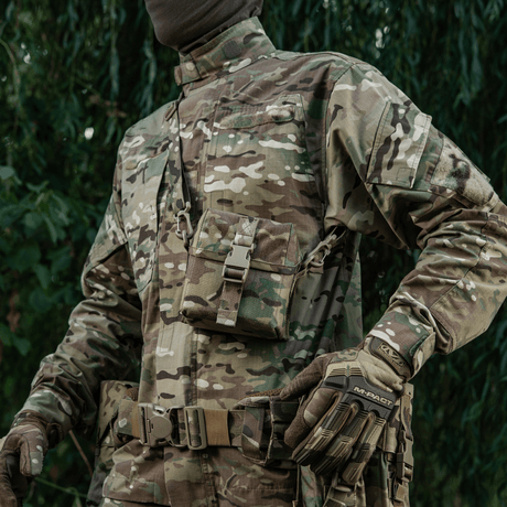 Person iført camouflageuniform med M-Tac Taske til Natkikkert PVS-14 hængende fra skulderen, udendørs baggrund.