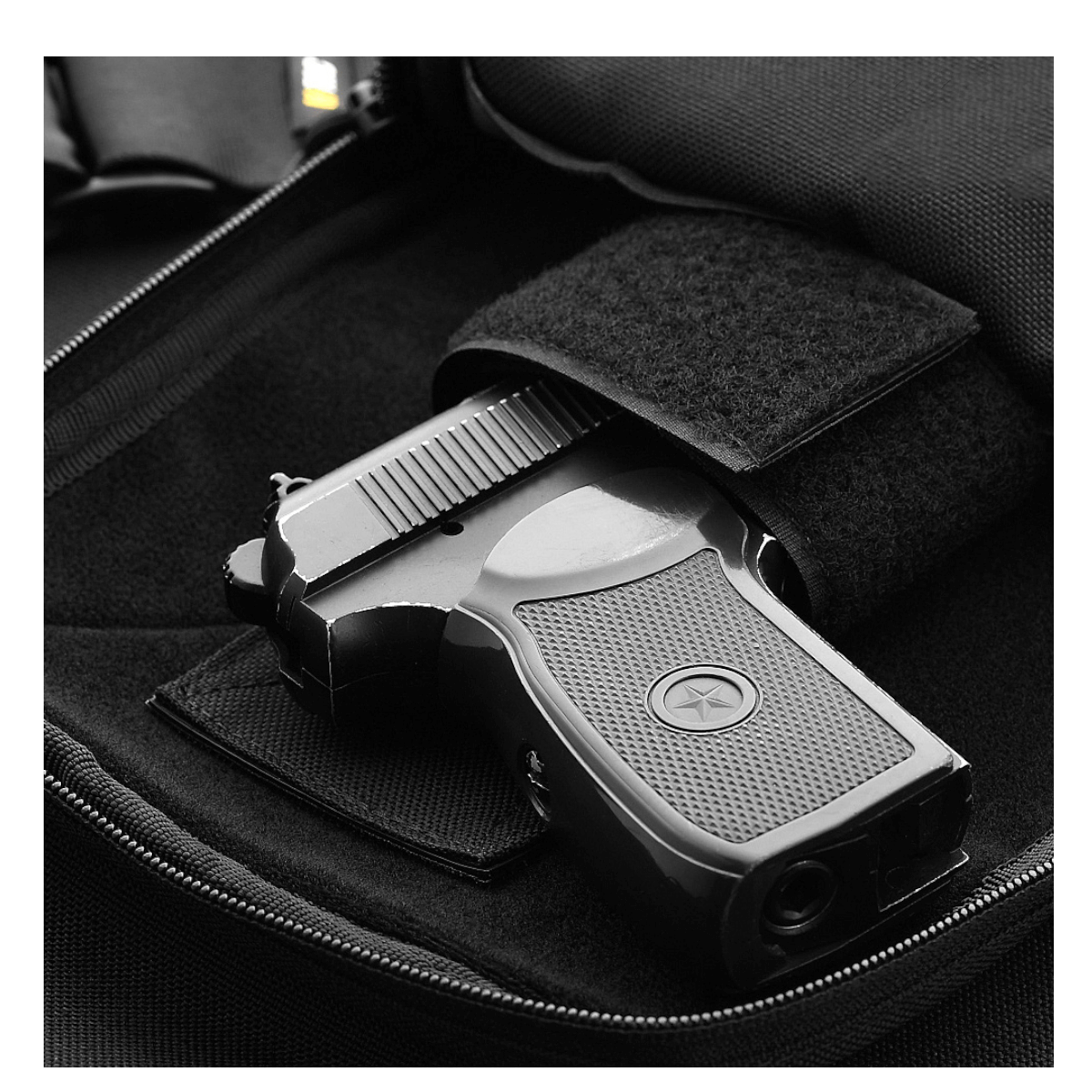 Pistol i M-Tac Carry Sling Taske Elite Gen.IV med Velcro, designet til skjult bæring med universelt velcro-hylster, klar til hurtig adgang.