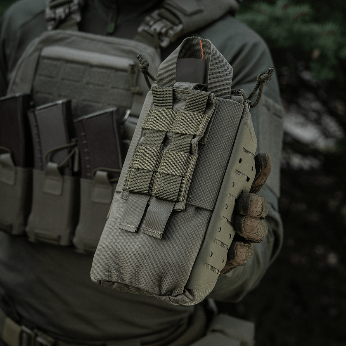 M-Tac Medical Pouch Elite Rip Off holdt af en person iført taktisk udstyr; kompakt førstehjælpstaske til hurtig adgang