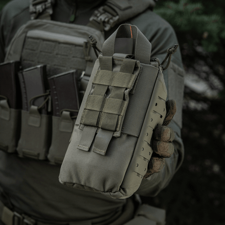 M-Tac Medical Pouch Elite Rip Off holdt af en person iført taktisk udstyr; kompakt førstehjælpstaske til hurtig adgang