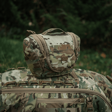 Kompakt camouflage M-Tac Toilettaske Elite Gen.II placeret på en rygsæk udendørs.