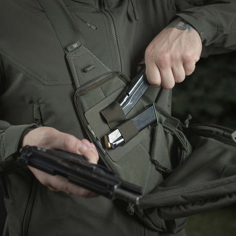 Henkilö käyttää M-Tac Double Mag Pouch Hook Backed Magazinea pistoolin lippaiden säilytykseen taktisessa laukussa