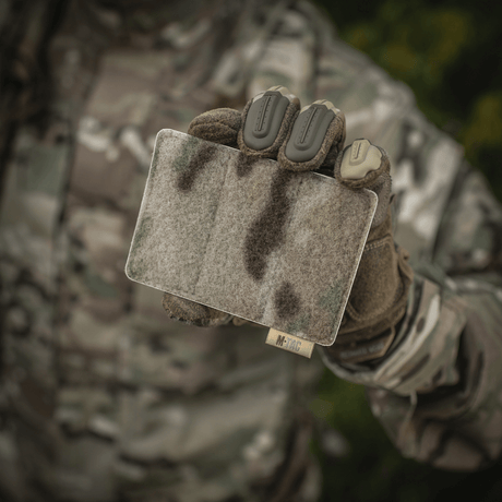 M-Tac paneeli patcheille MOLLE 120x85 camo-yksityiskohdalla, pidetään taktisia varusteita käyttävän henkilön kädessä, hook & loop overflade