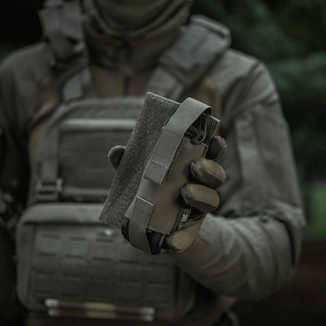 M-Tac Tourniquet Pouch Elastisk VELCRO Gen.II taktisen varusteisen henkilön kädessä nopeaan pääsyyn tourniquetiin