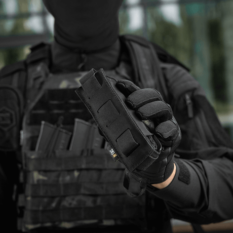 M-Tac Tourniquet Pouch Elastisk med MOLLE Gen.II käytössä, henkilö taktiikkavarusteissa pitää sitä, tarjoaa nopean pääsyn.