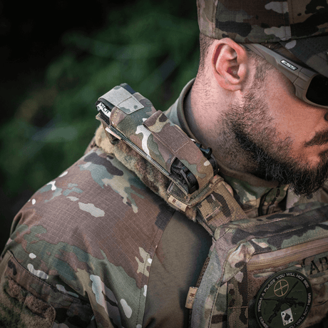 Sotilas kantaa M-Tac Tourniquet Pouch Elastisk med MOLLE Gen.II:tä nopeaa pääsyä ja turvallista tourniquet-säilytystä varten MOLLE-varusteissa.