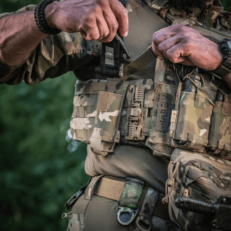 Sotilas kantaa M-Tac Tourniquet Pouch Elastisk med MOLLE Gen.II -koteloa sotilasvarusteissa luonnonympäristössä.