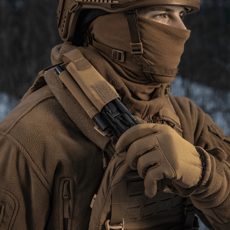 Taktiikka-asuun pukeutunut henkilö, jolla M-Tac Elastinen turnikekotelo Molle Gen.III kiinnitettynä olkapäähän talvimaisemassa.