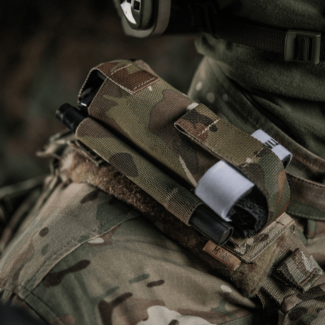 M-Tac Elastinen turnikekotelo Molle Gen.III kiinnitetty armeijan liiviin camossa, tarjoaa helpon pääsyn C-A-T tourniquettiin.