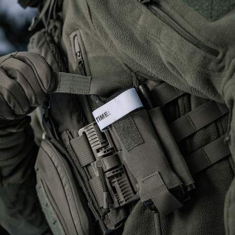 M-Tac Elastinen turnikekotelo Molle Gen.III kiinnitetty taktiseen liiviin, näyttää käytännöllistä käyttöä ja helpon pääsyn tourniquettiin.