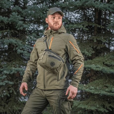 Mies kantaa M-Tac Sphaera Hex Hardsling Gen.II Elite metsäalueella.
