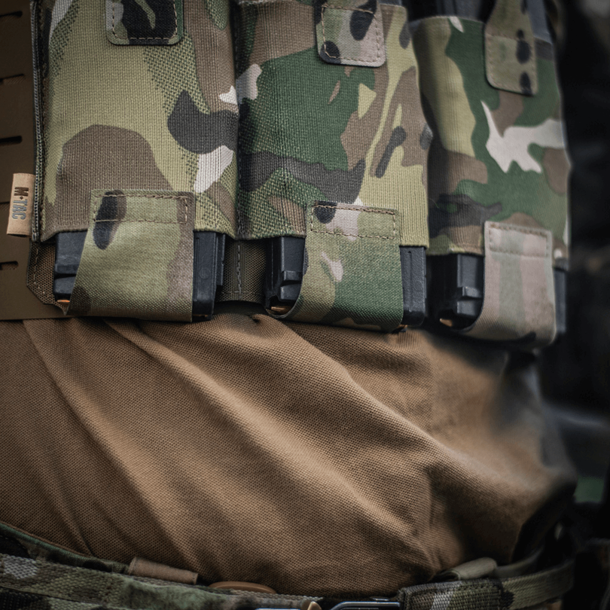 M‑Tac Elastisk Single Magazine Pouch Elite monteret på taktisk vest med camouflage, fremhæver MOLLE kompatibilitet og hurtig adgang.