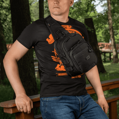 Mies kantaa M‑Tac Cross Bag Elite Hex -sling-laukkua, Cordura 500, sopii päivittäiskäyttöön ja taktiseen varustukseen