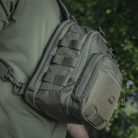 M‑Tac Cross Bag Elite Hex sling-laukku Cordura 500:sta, nähty olalla vihreässä ympäristössä, sopii päivittäiseen käyttöön ja taktisiin varusteisiin. 5 l.