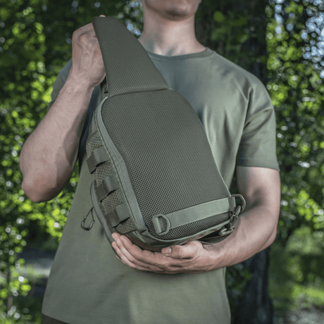 Mies kantaa M‑Tac Cross Bag Elite Hexiä, kompakti laukku ja reppu Cordura 500:sta, sopii päivittäiseen käyttöön ja taktisiin varusteisiin.