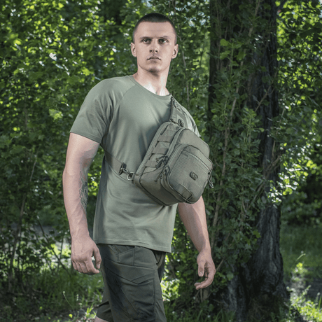 Mies kantaa M‑Tac Cross Bag Elite Hexiä metsäympäristössä, sopii päivittäiseen käyttöön ja taktisiin varusteisiin.