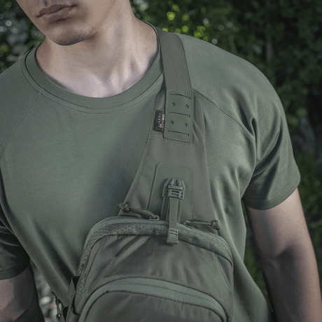 M‑Tac Cross Bag Elite Hex käytössä henkilöllä, joka pitää vihreää T-paitaa, sopii sekä arkeen että taktisiin varusteisiin.