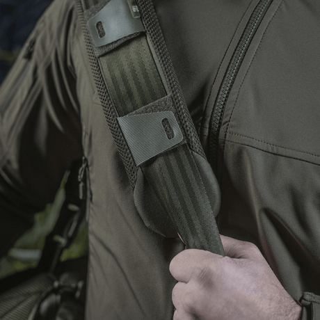 Mies kantaa M‑Tac olkahihnan pehmikettä 50 mm Elite olkapäällä mukavuutta ja tukea varten.