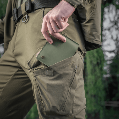 M-Tac Slim Elite Gen. II vihreänä vedetään housuntaskusta, näyttää kompaktin muodon ja modernin valmistusteknologian.