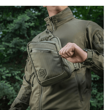 Henkilö kantaa M-Tac Sling Pistoltaske Elite Hexitä ulkona mukavassa ja kestävässä laukussa, säädettävä hihna ja tilavat osastot.