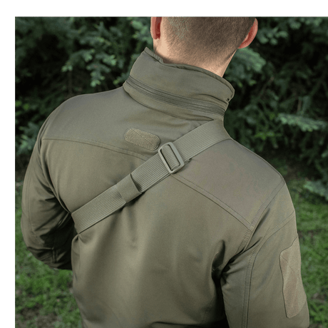 Mies kantaa M-Tac Sling Pistoltaske Elite Hexiä säädettävällä olkahihnalla ulkoilmassa.