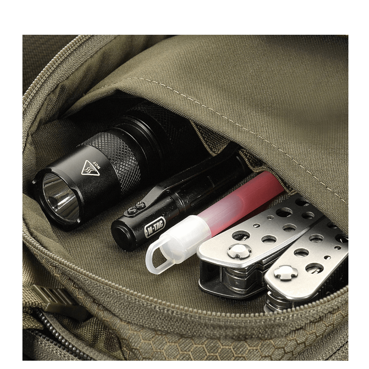 Detalje af M-Tac Sling Pistoltaske Elite Hex med lommelygte, multitool og kuglepen synlige i lommen.