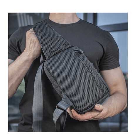 Henkilö kantaa M-Tac Sling Pistoltaske Elite Hexiä, mukava ja kestävä laukku säädettävällä olkahihnalla ja kestävästä materiaalista.