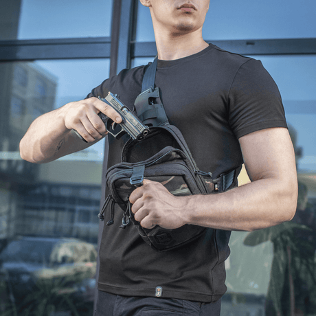 Mies M-Tac Sling Pistoltaske Elite Hex -laukun kanssa, esittelee piilotetun aseen käyttöä. Mukava ja kestävä laukku diskreettiin kuljetukseen.