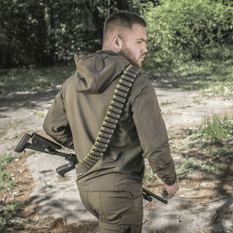 Metsästäjä pukeutuneena M-Tac Bandolier Eliteen ammuksineen metsäympäristössä.