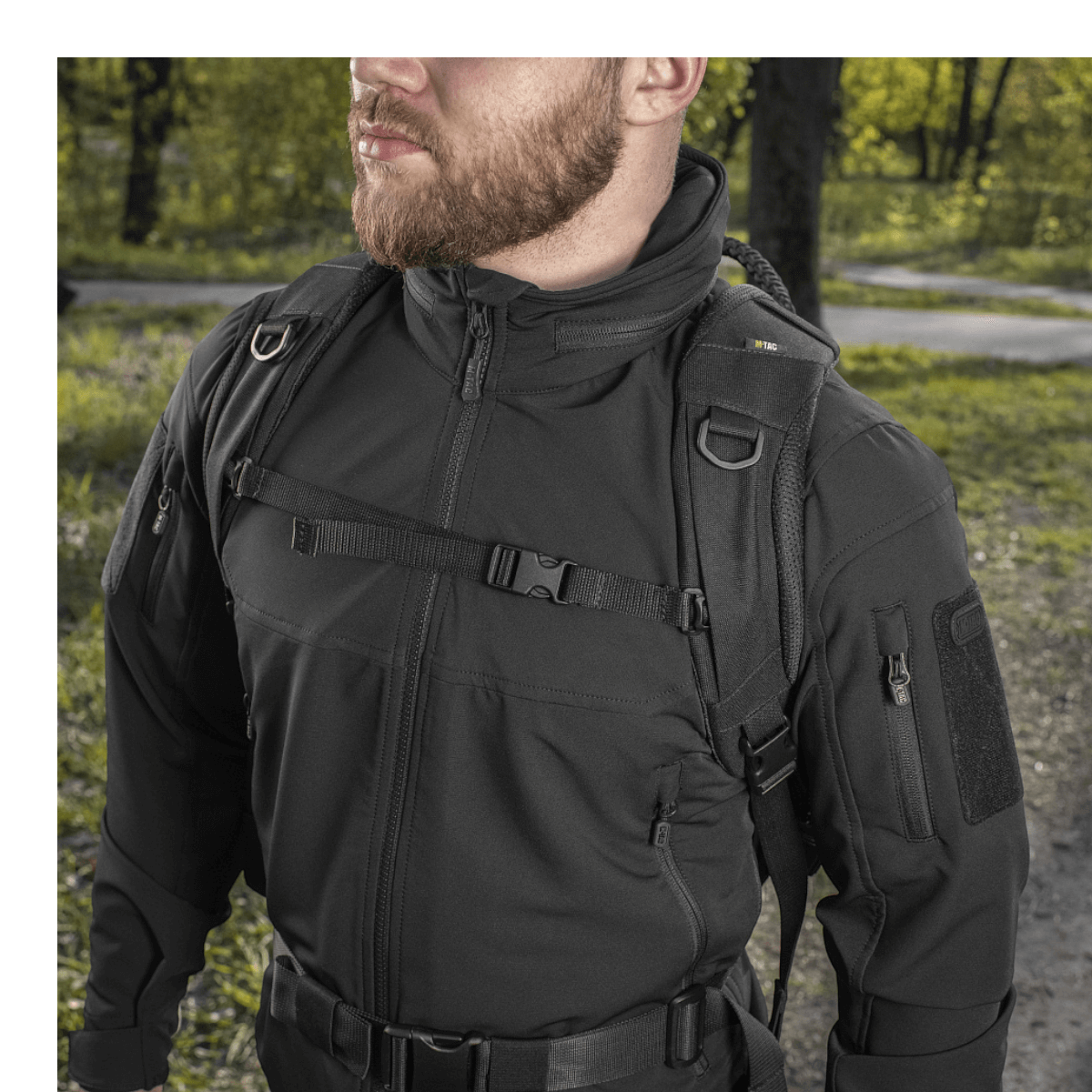 Mand bærer M-Tac Mission Pack Elite-rygsæk i skovområde, viser holdbarhed og stilfuldt design i Cordura 1000D stof.