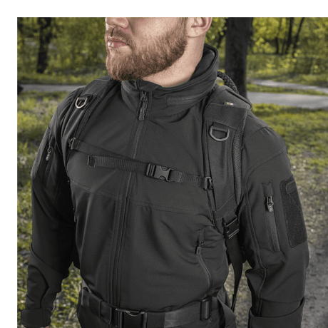 Mies kantaa M-Tac Mission Pack Elite -reppua metsäalueella, korostaen Cordura 1000D -kankaan tyylikästä muotoilua.