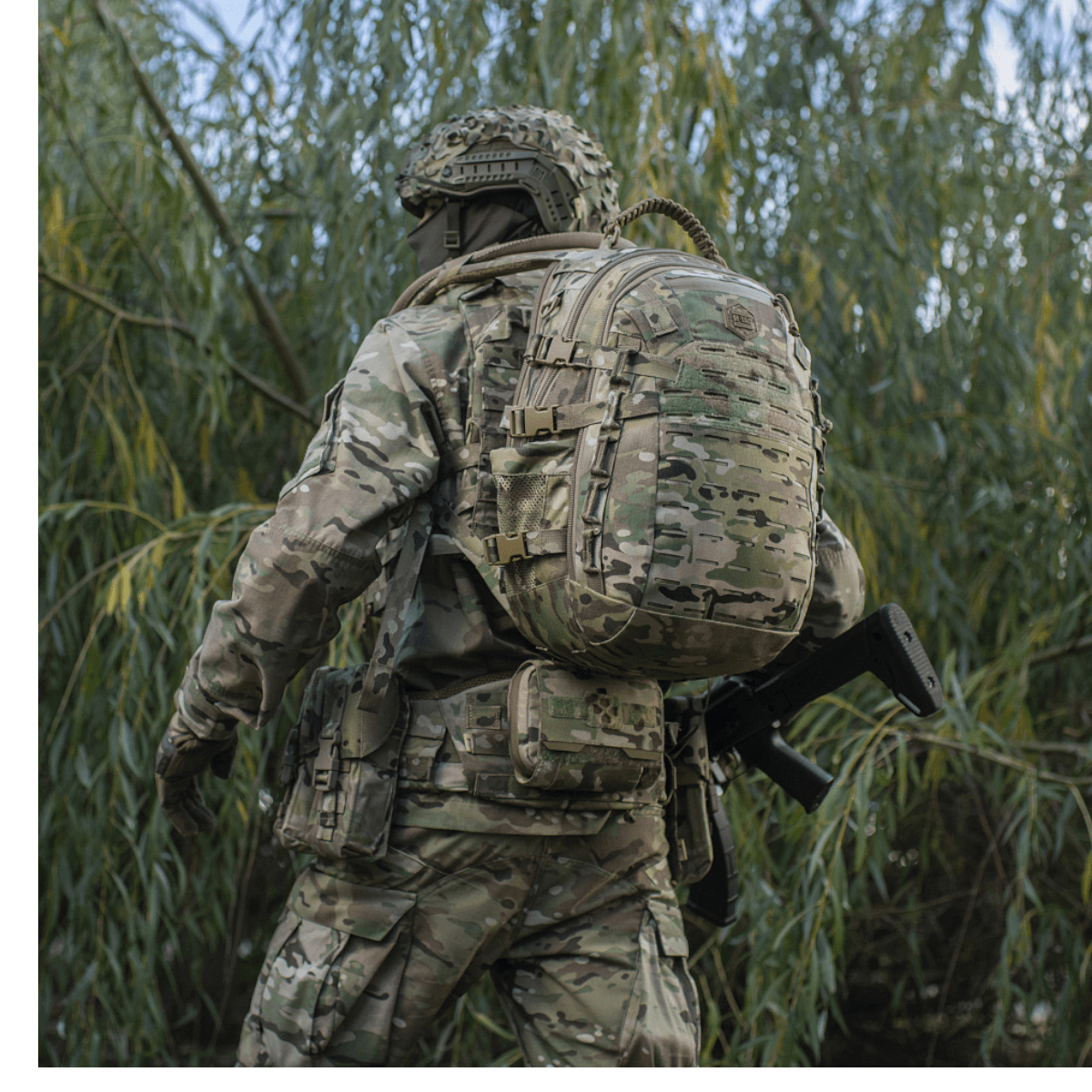 Soldat med M-Tac Mission Pack Elite rygsæk i camouflage, i naturmiljø.