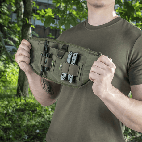 Mies esittelee M‑Tac Bæltetaske Elite Hexiä työkaluineen, ihanteellinen taktiseen ja arjen käyttöön, valmistettu Cordurasta modulaarisilla taskuilla.
