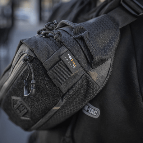 M‑Tac Elite Hex -vyölaukku näkyvissä kantajana, valmistettu Cordurasta ja varustettu YKK-vetoketjuilla, sopii päivittäiseen tai taktiseen käyttöön.
