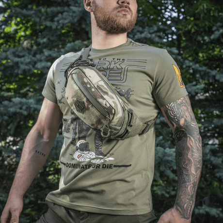 M‑Tac Elite Hex -vyölaukku miehellä metsässä, tyylikäs ja toimiva Cordura-materiaalin ja taktisten taskujen ansiosta.