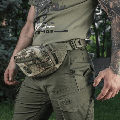 M-Tac Elite Hex -vyölaukku camo-kuosissa, kulutusta kestävä Cordura-materiaali, henkilöllä vihreä ulkoiluvaatetus.