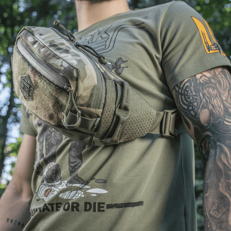M‑Tac Elite Hex -vyölaukku miehellä camo-kuosissa, sopiva taktiseen varustukseen ja päivittäiseen käyttöön, valmistettu Cordura-materiaalista.