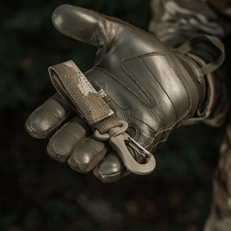 M-Tac Karabinhage Tilbehør siddende på militærhandske med MOLLE-system og Velcro-rem for sikker fastgørelse af udstyr.
