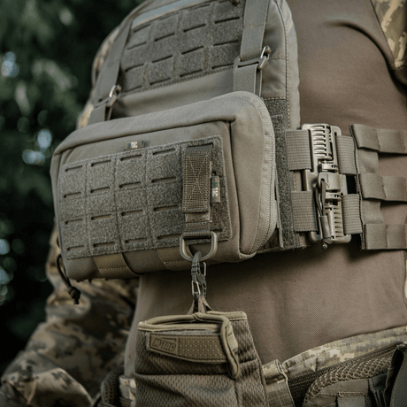 M-Tac-kiinnike D-renkaalla asennettuna taktiseen liiviin, MOLLE-järjestelmä ja Velcro-suljin.