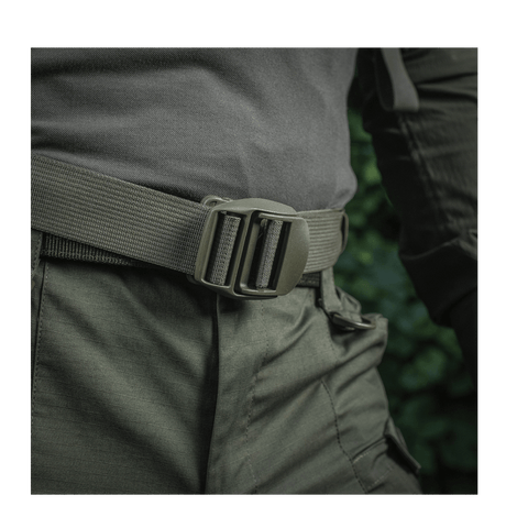 Mies pukeutuneena M-Tac Mission Rygsæk Elite Hex -reppuun Cordura-materiaalista ja MOLLE LASER CUT -järjestelmällä, lähellä vyötä.
