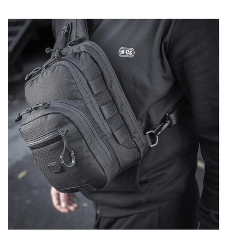 M-Tac Cross Taske Slim Elite Hex kannettuna olalla, näyttää tyylikkään muotoilun ja kestävän Cordura-kankaan.