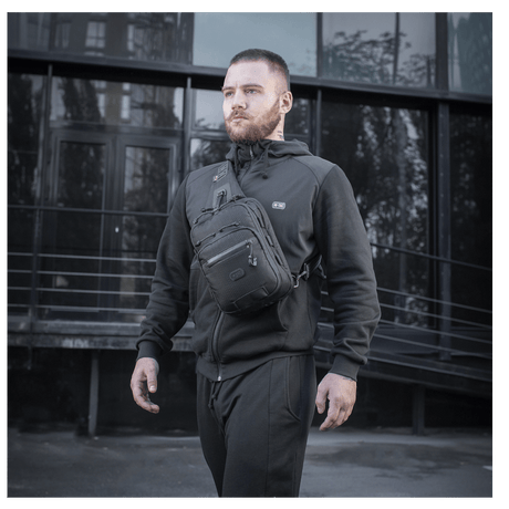 Mies kantaa M-Tac Cross Taske Slim Elite Hex -laukkua, tyylikäs ja toimiva laukku Cordura-materiaalista, varusteina YKK ja Woojin.