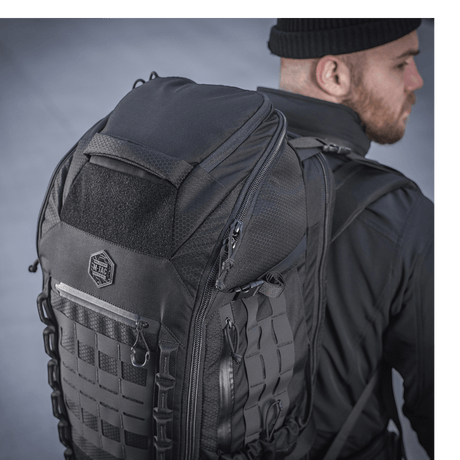 M-Tac Rygsæk Large Elite Hex Gen. IV henkilön selässä mustissa vaatteissa, näyttää kestävyyden ja tyylikkään muotoilun Cordura-materiaalissa.