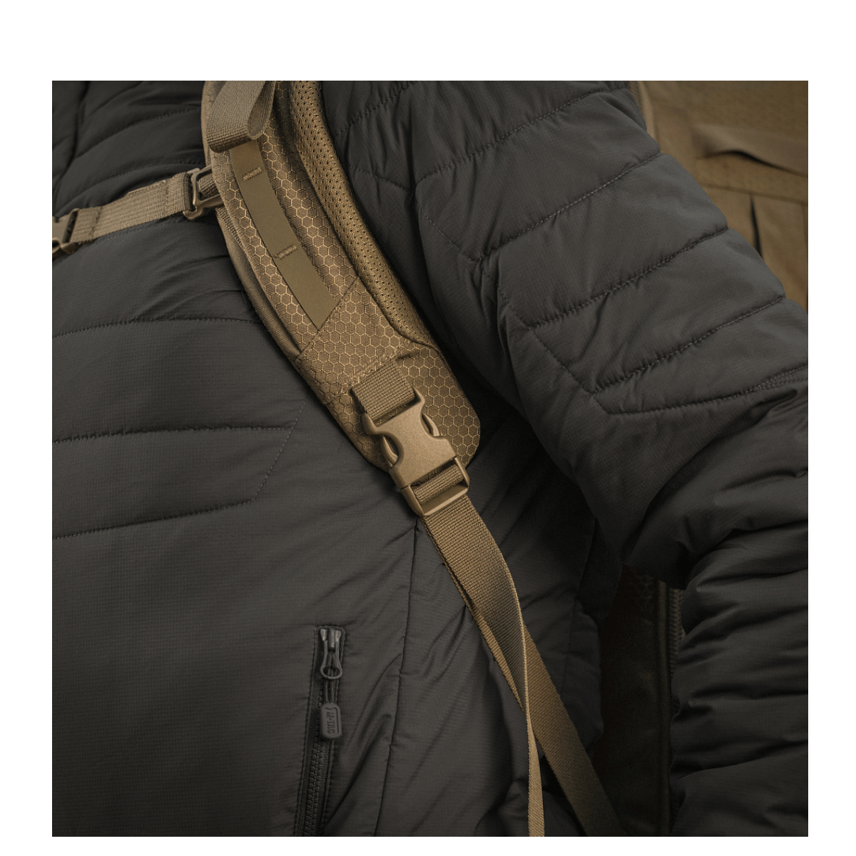 Person med sort jakke bærer M-Tac Rygsæk Large Elite Hex Gen. IV med justerbare stropper og ergonomisk design.