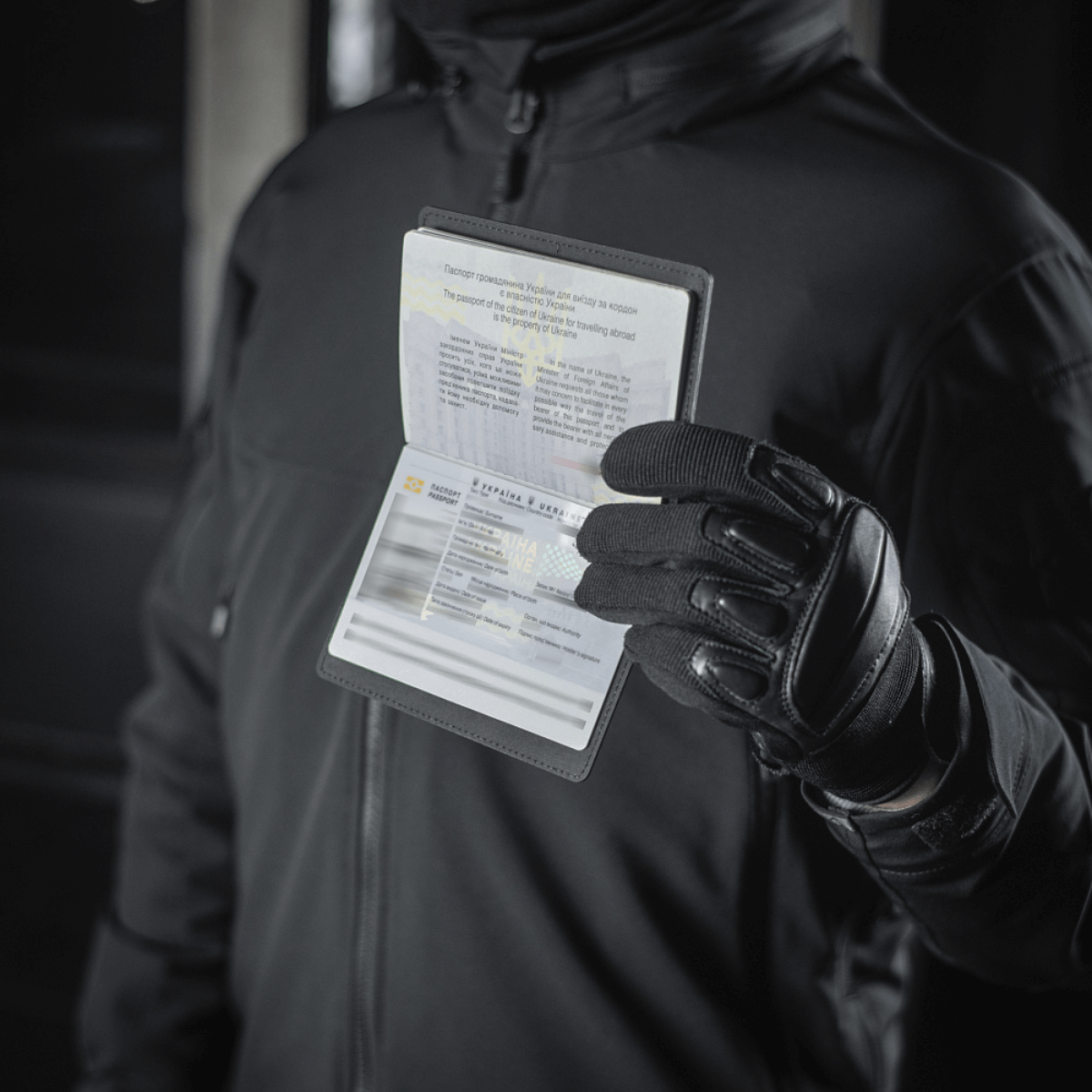Person med M‑Tac Pascover holder et pas, beskytter mod slid og skader, moderne polymer, stilfuldt design, ideel til rejser.