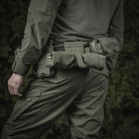 Mies pukeutuneena taktiseen varustukseen, M‑Tac Magasinsæk Dump Pouch Lite Elite kiinnitettynä vyöhön tehokkaaseen lippaiden käsittelyyn.